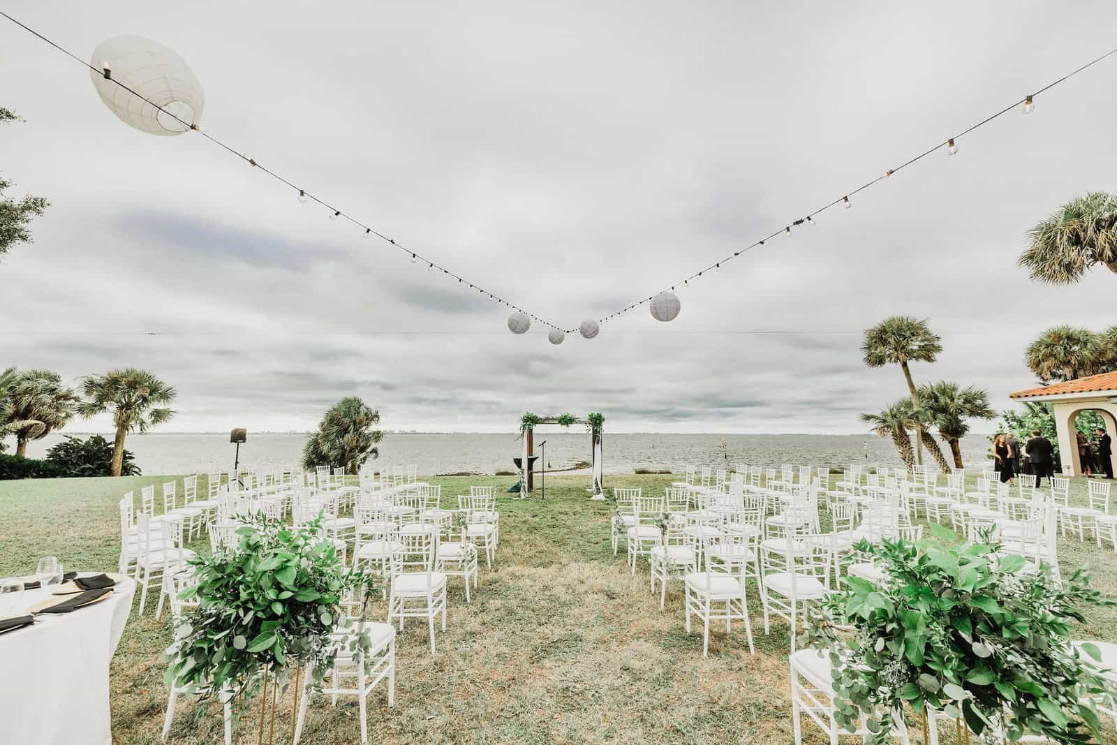 White chiavari chairs arranged in concentric circular rows facing the waterfront ceremony chuppah