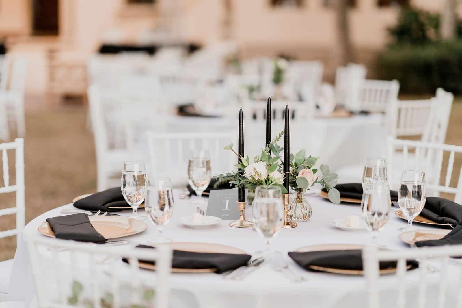 Black taper candles in gold holders with gold chargers and terracotta floral accents
