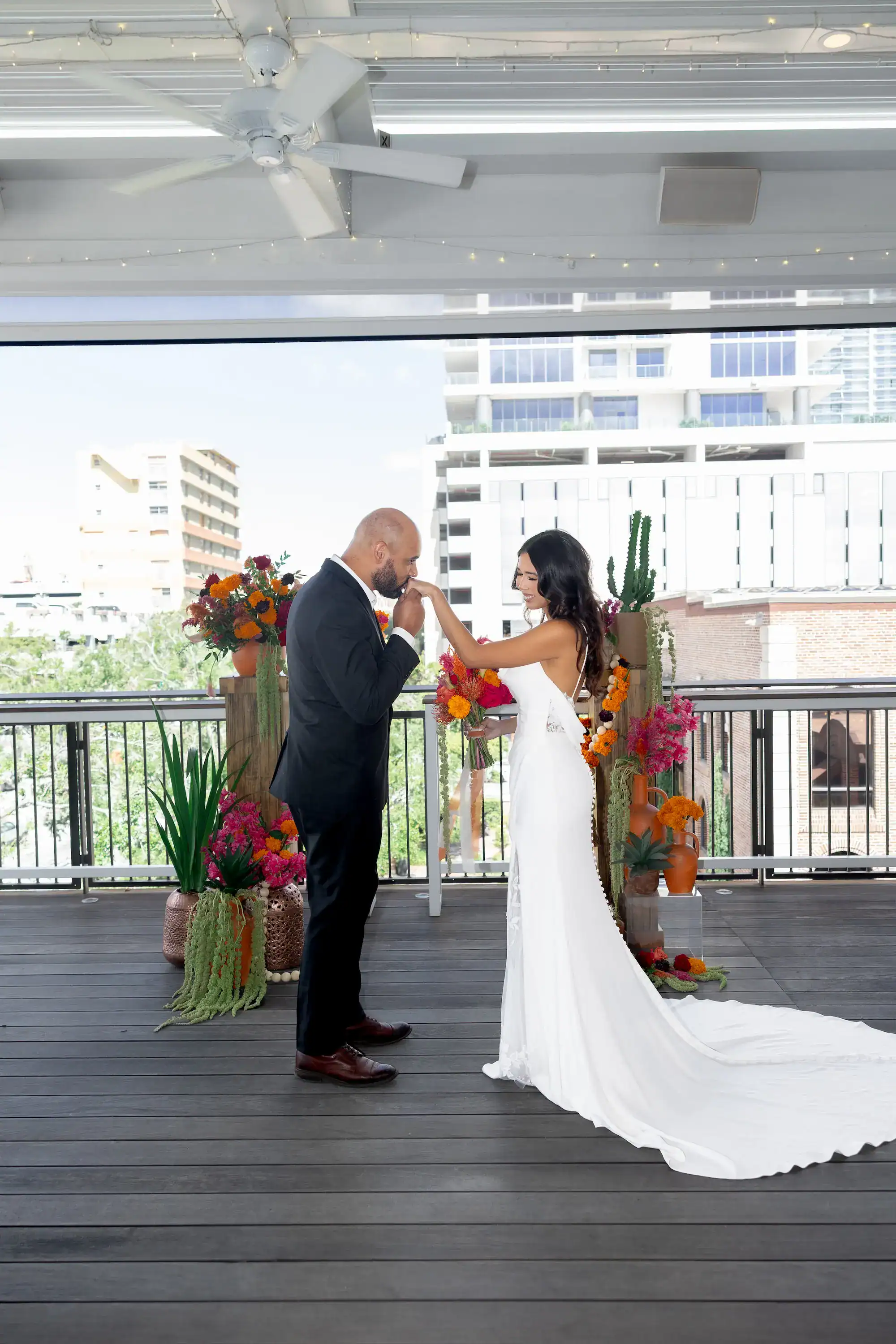 Bride and Groom at Altar with Vibrant Terracotta and Pink Florals on Balcony Terrace