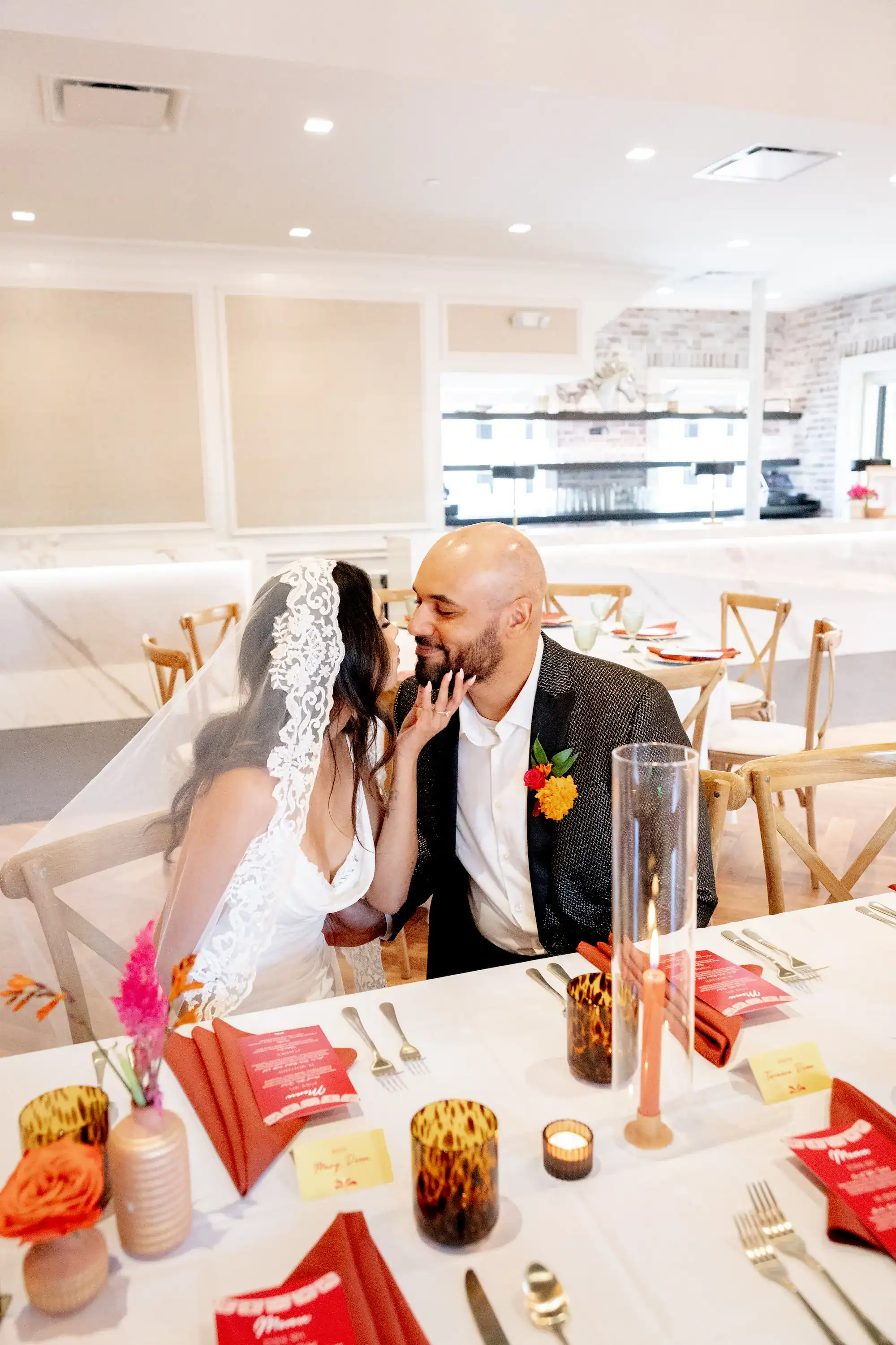 Bride and Groom Seated at Wedding Reception Table with Rustic Wooden Chairs