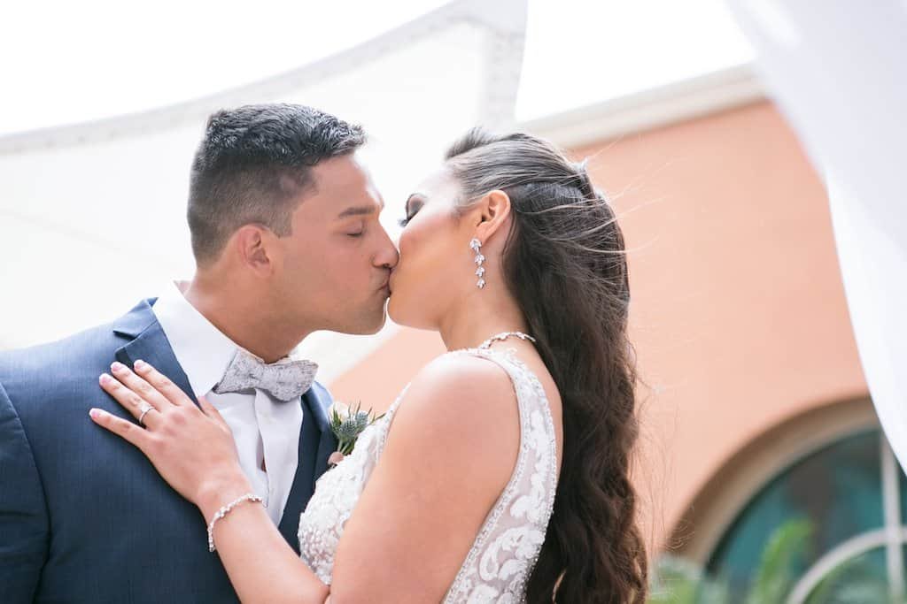 Outdoor Courtyard Fountain Ceremony Arch with White Hydrangeas Dusty Blue Flowers and Lush Greenery by Gabro Event Services