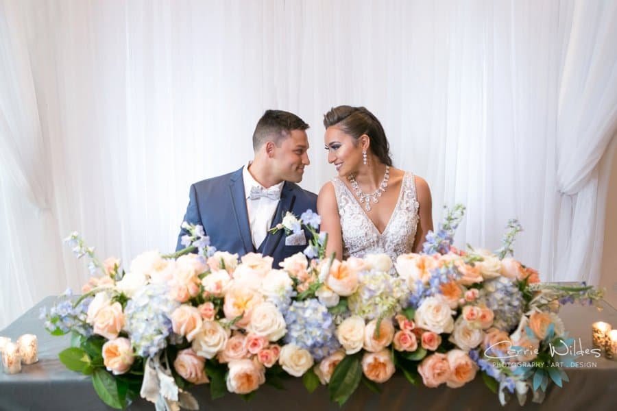Sophisticated bride in modern gown and groom in tailored tuxedo posing in the chic modern lobby of Renaissance Tampa