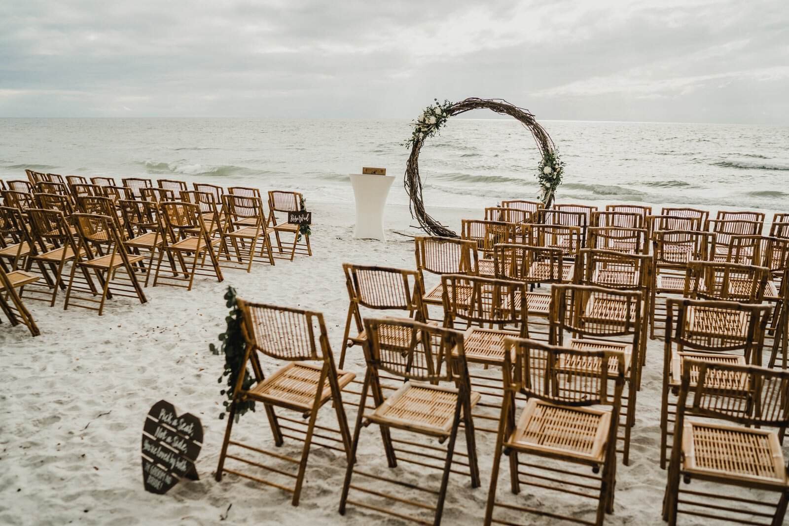 Natural wood chairs arranged in rows for an oceanfront wedding ceremony setup.