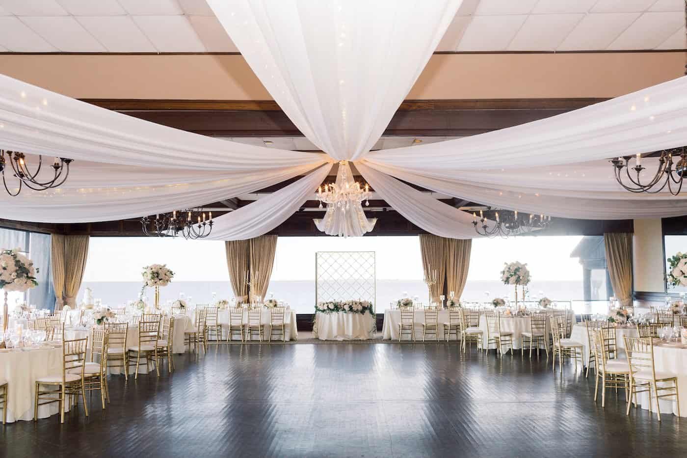 Grand Ballroom Reception at The Rusty Pelican with Ceiling Draping Chandeliers and Gold Chiavari Chairs by Gabro Event Services