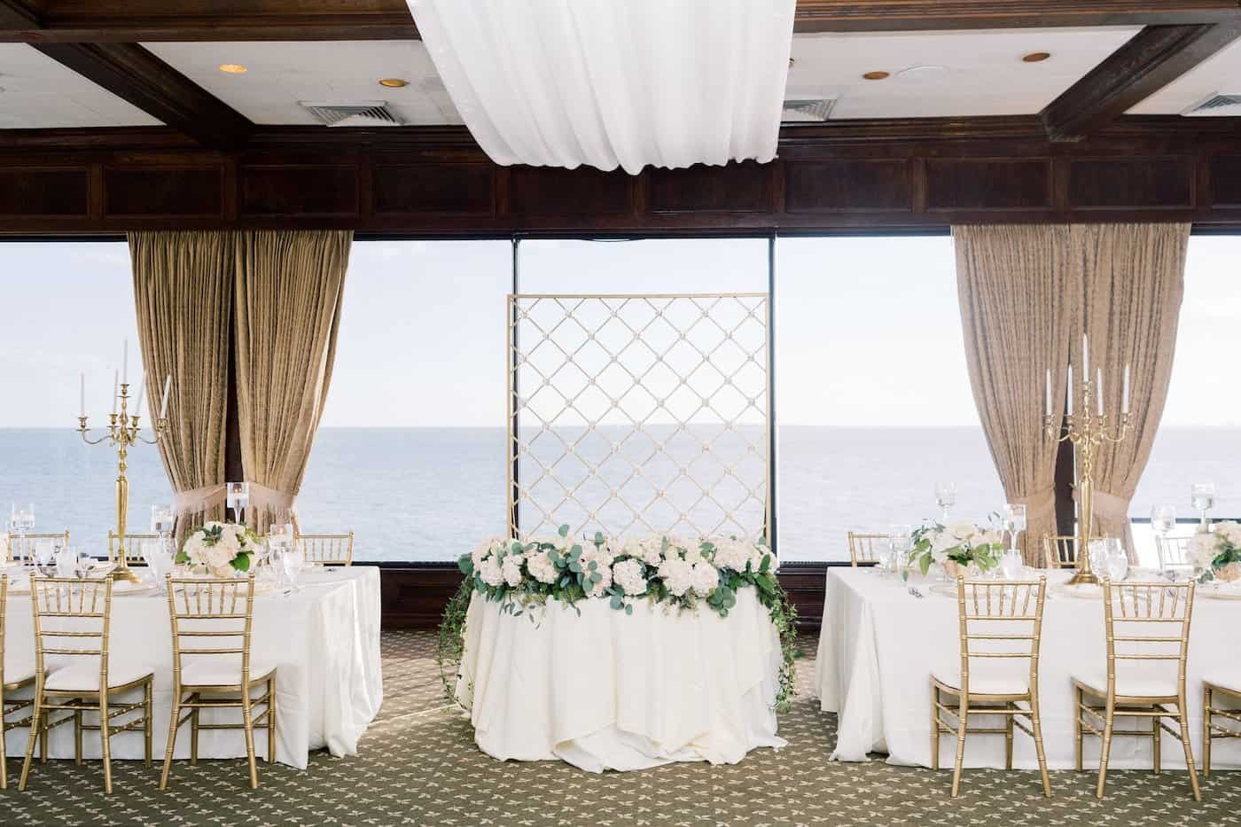 Sweetheart Table with Criss Cross Gold Backdrop and Floral Garland by Gabro Event Services at The Rusty Pelican