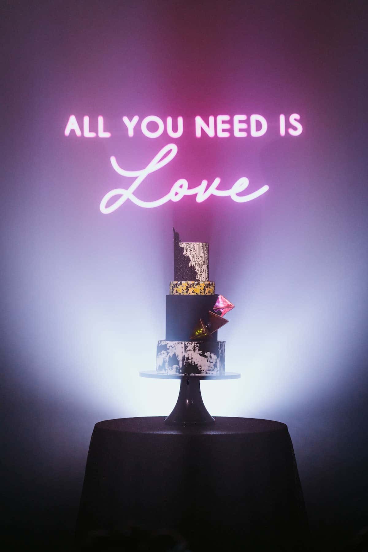 Four Tier Geometric Marble Black and Gold Wedding Cake Before Neon Backdrop