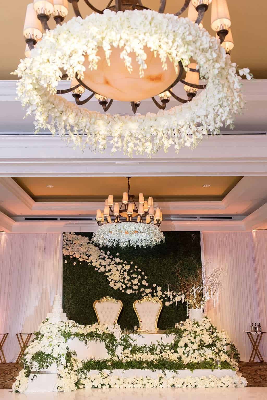 Luxury Sweetheart Table with Hanging Chandelier Florals and White Draping by Gabro Event Services at Sandpearl Resort