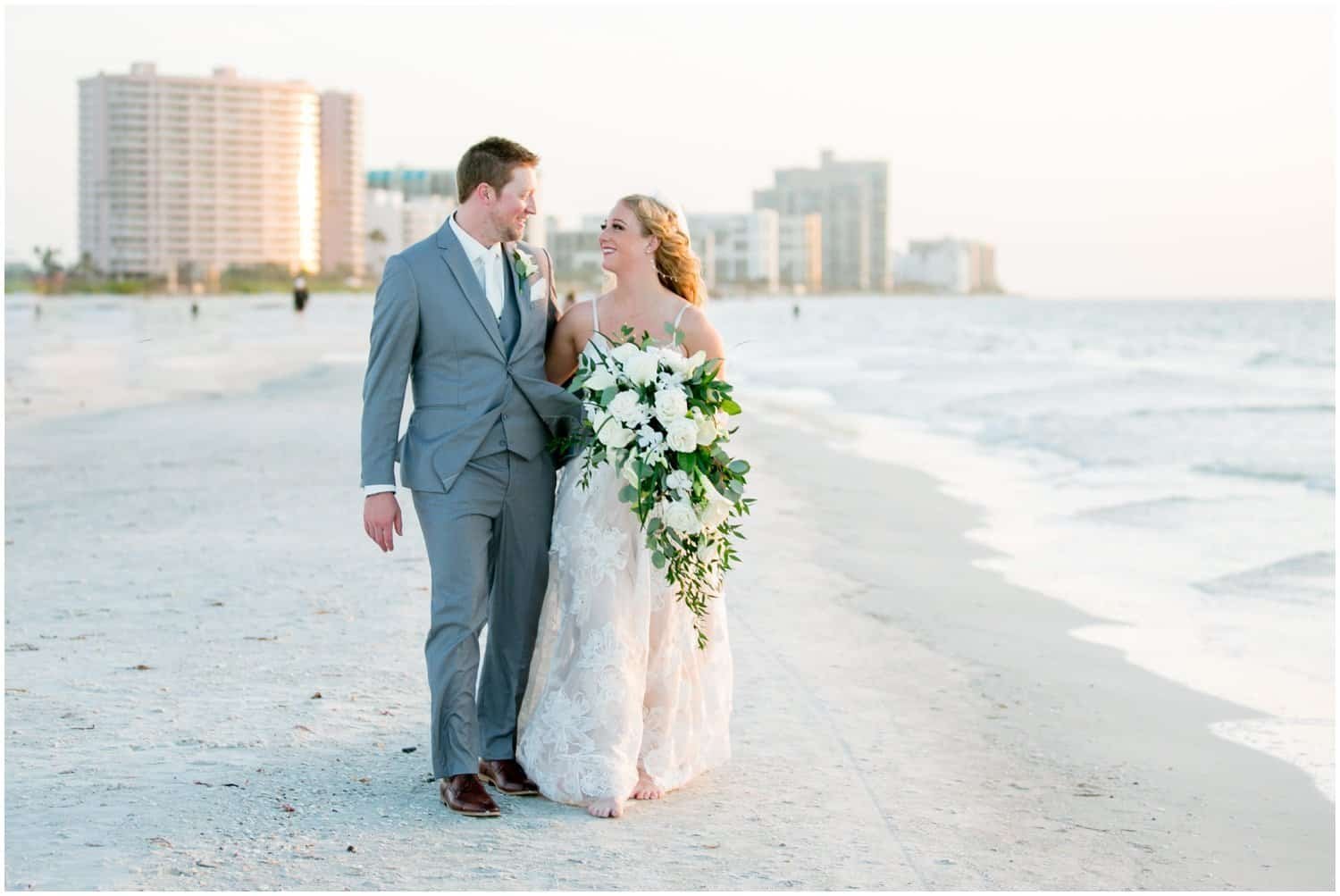 Custom ceremony wedding arch adorned with fresh tropical greenery on the white sand beach at Sheraton Sand Key Resort