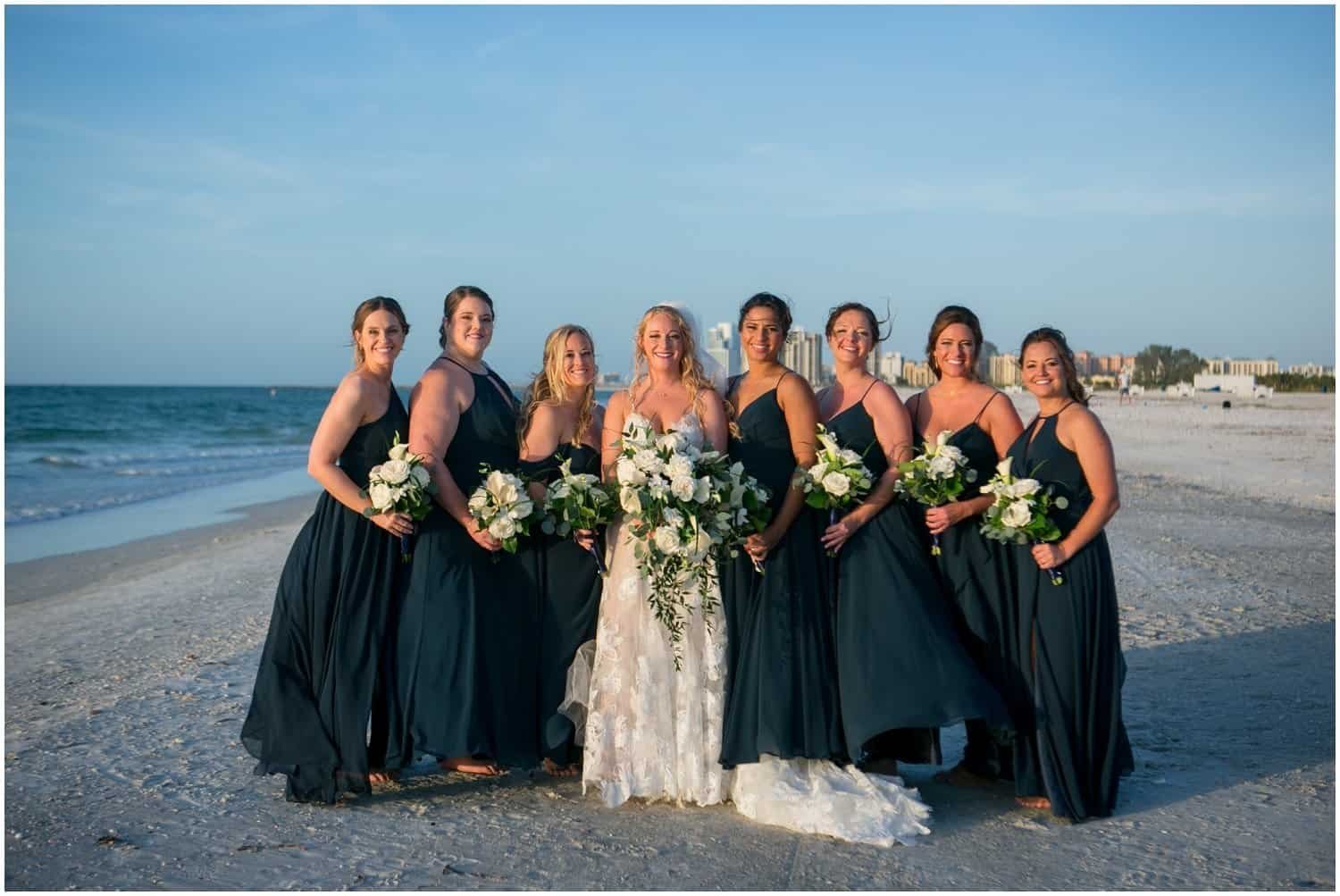 Wedding party and guests celebrating under vibrant pink and orange sunset skies at Sheraton Sand Key