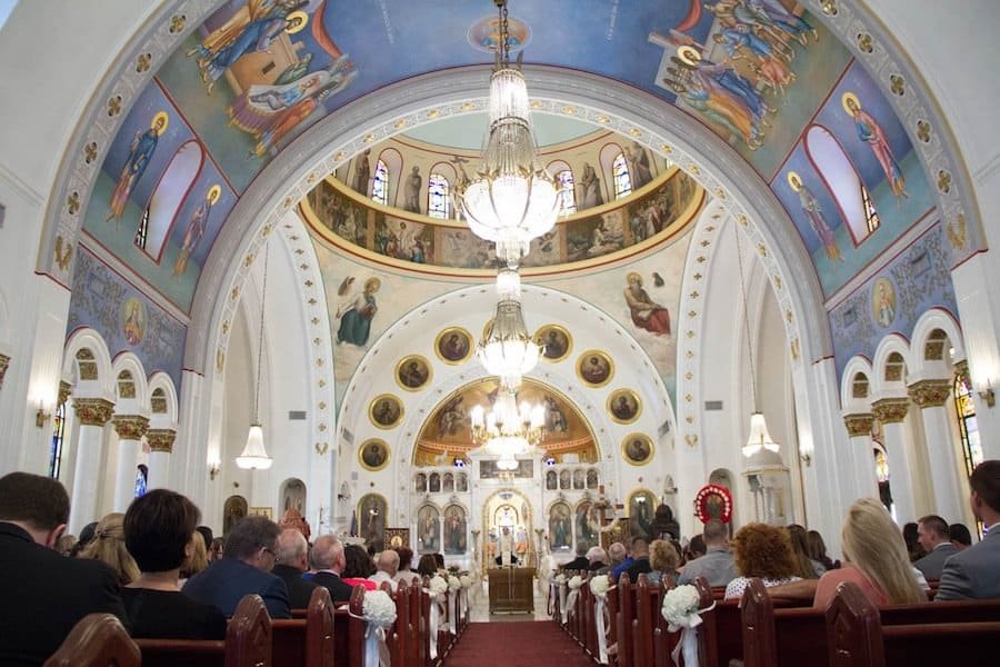 Greek Orthodox bride and groom wearing golden Stefana wedding crowns during sacred marriage ceremony in Tarpon Springs