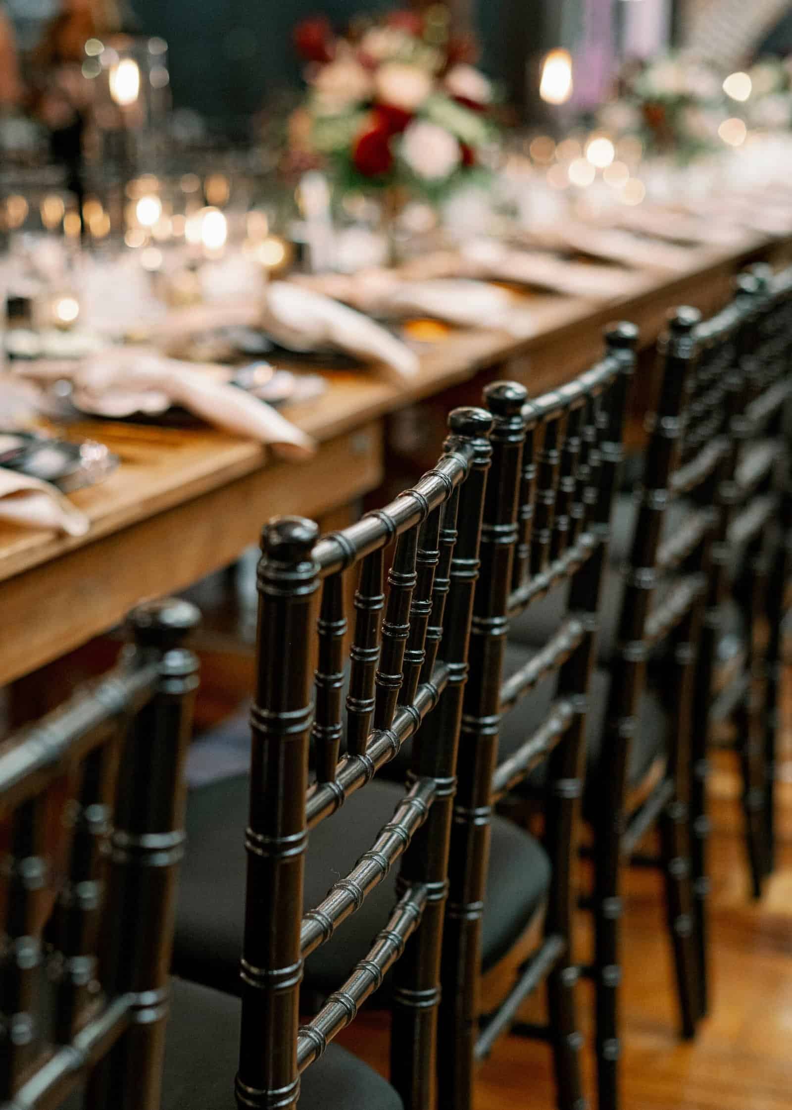 Candlelit farm table run with black Chiavari chairs down the length of the room at Station House