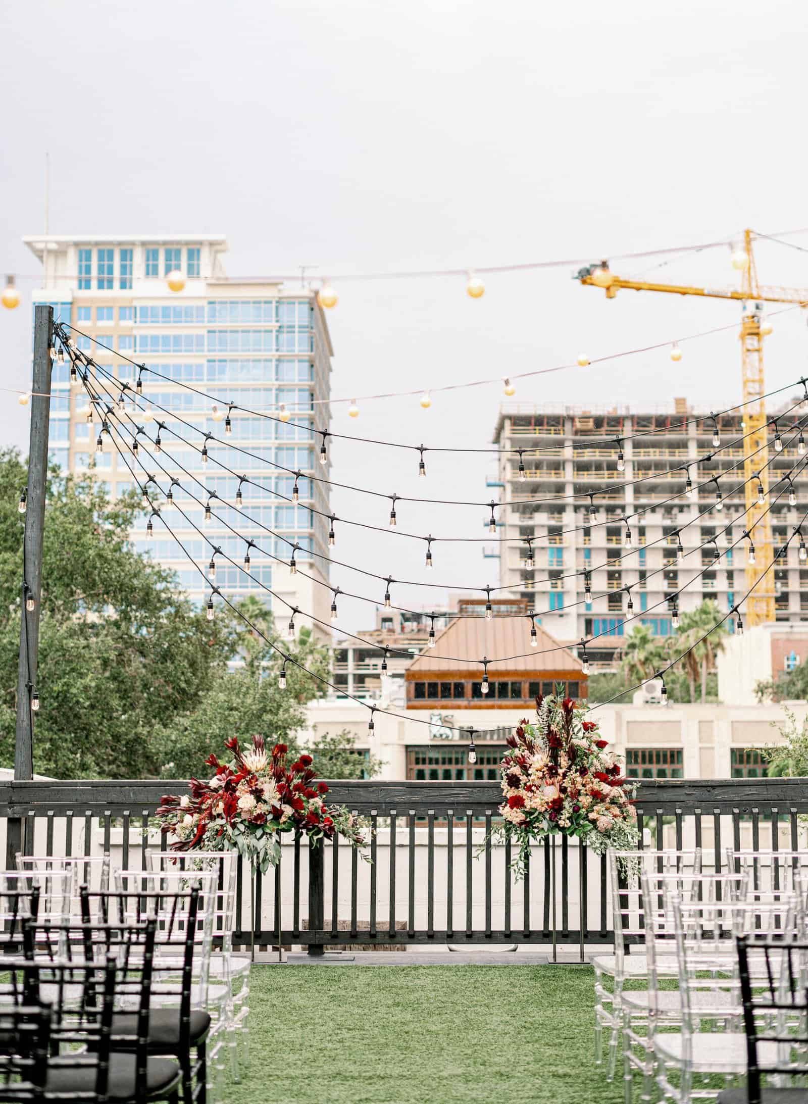 Ceremony aisle lined with rich burgundy floral compotes and black chiavari seating