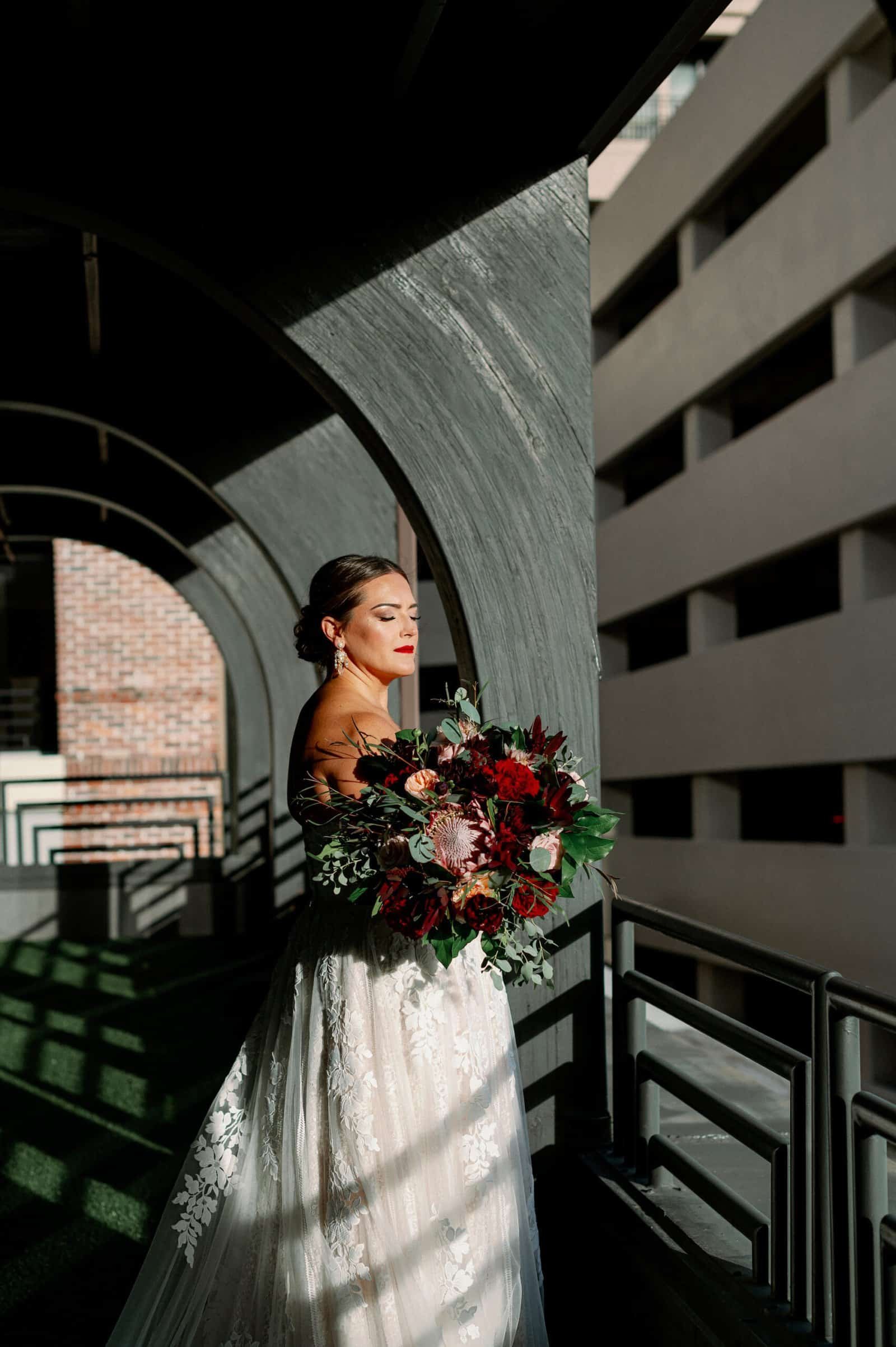 Bride bridal portrait with dramatic cascading burgundy bouquet and sweetheart lace gown