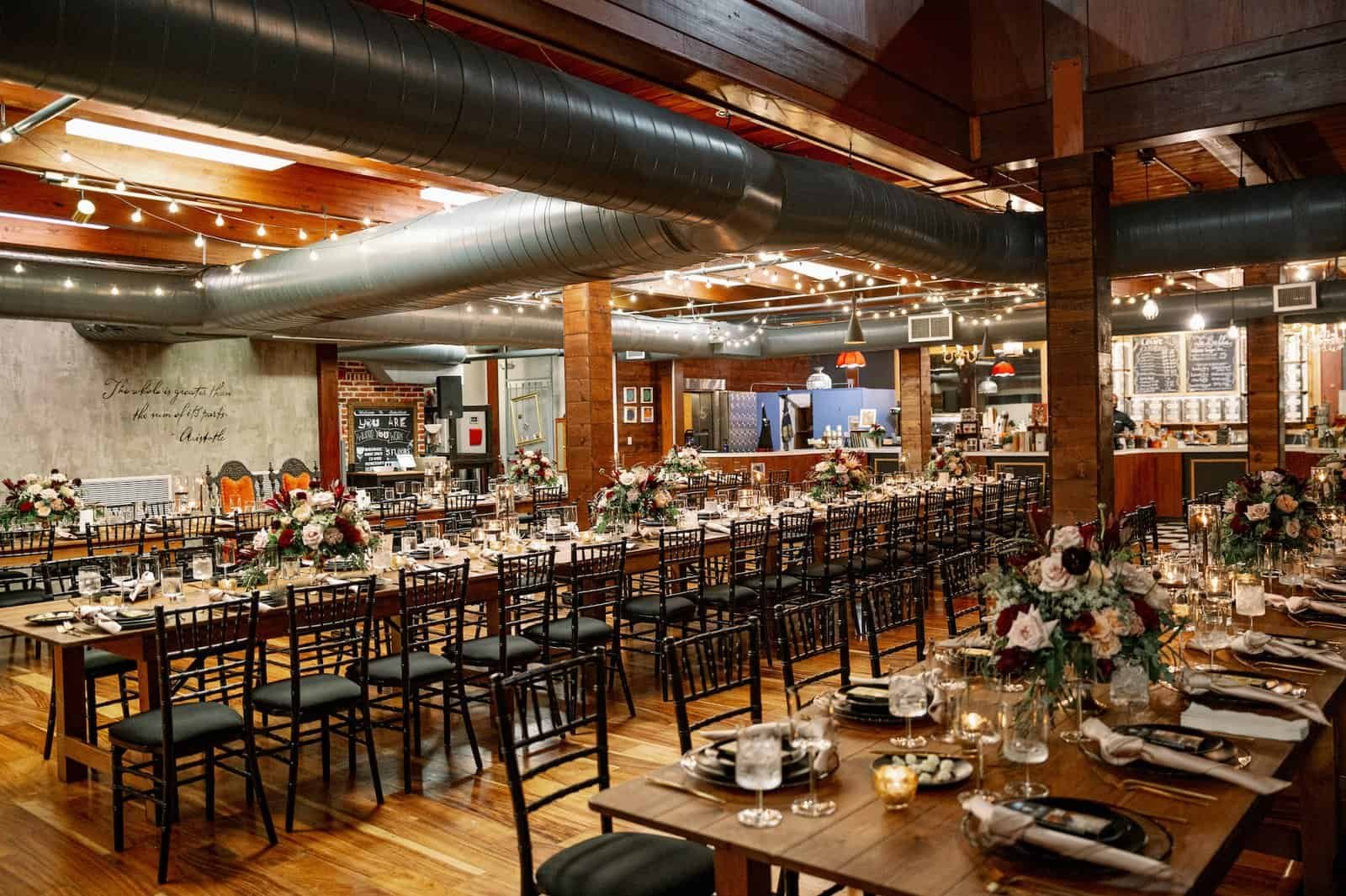 Industrial indoor reception with natural wood farm tables and onyx black chiavari chairs by Gabro Event Services