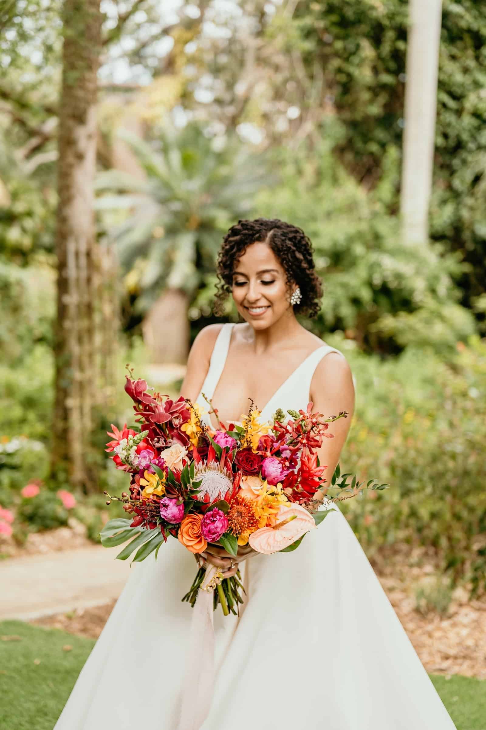 Tropical wedding reception tables featuring burgundy flowers and fresh citrus fruit accents.