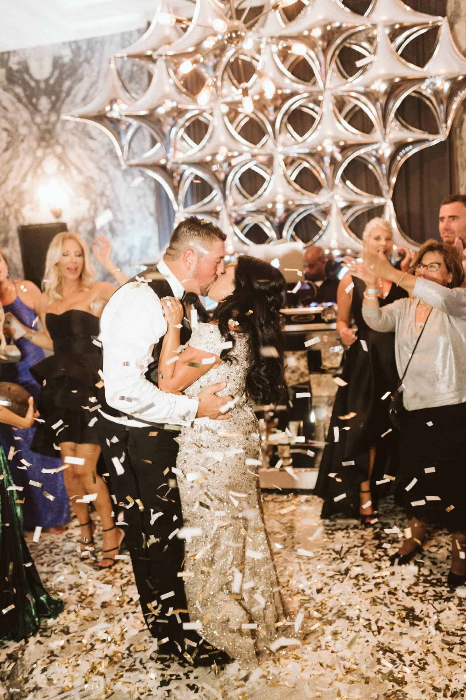 Bride and groom celebrating under a shower of gold confetti with dance floor reception lighting by Gabro Event Services at Le Méridien Tampa