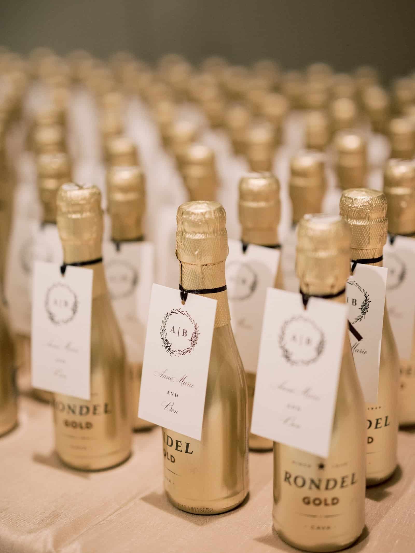 Gold mini champagne bottle splits with personalized escort cards arranged on a gilded guest seating table