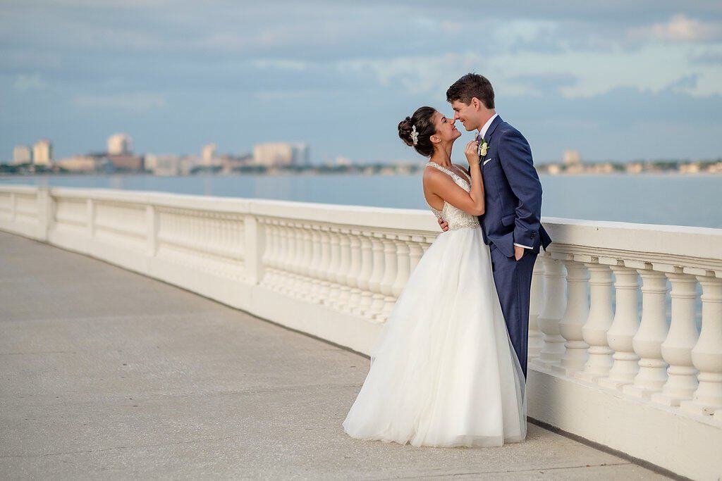 Bride in Madeline Gardner ballgown and groom in navy suit sharing a portrait along Bayshore Boulevard at the Tampa Garden Club