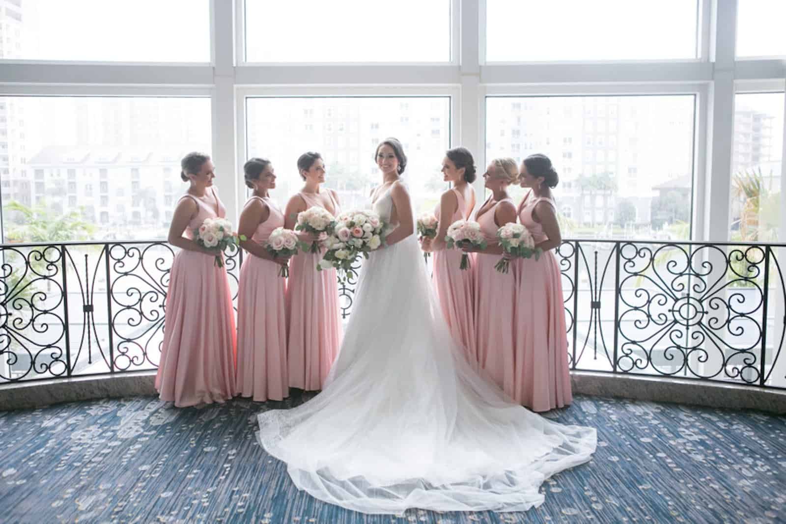 Elegant wedding reception tables featuring pink linens and gold accents in a ballroom.