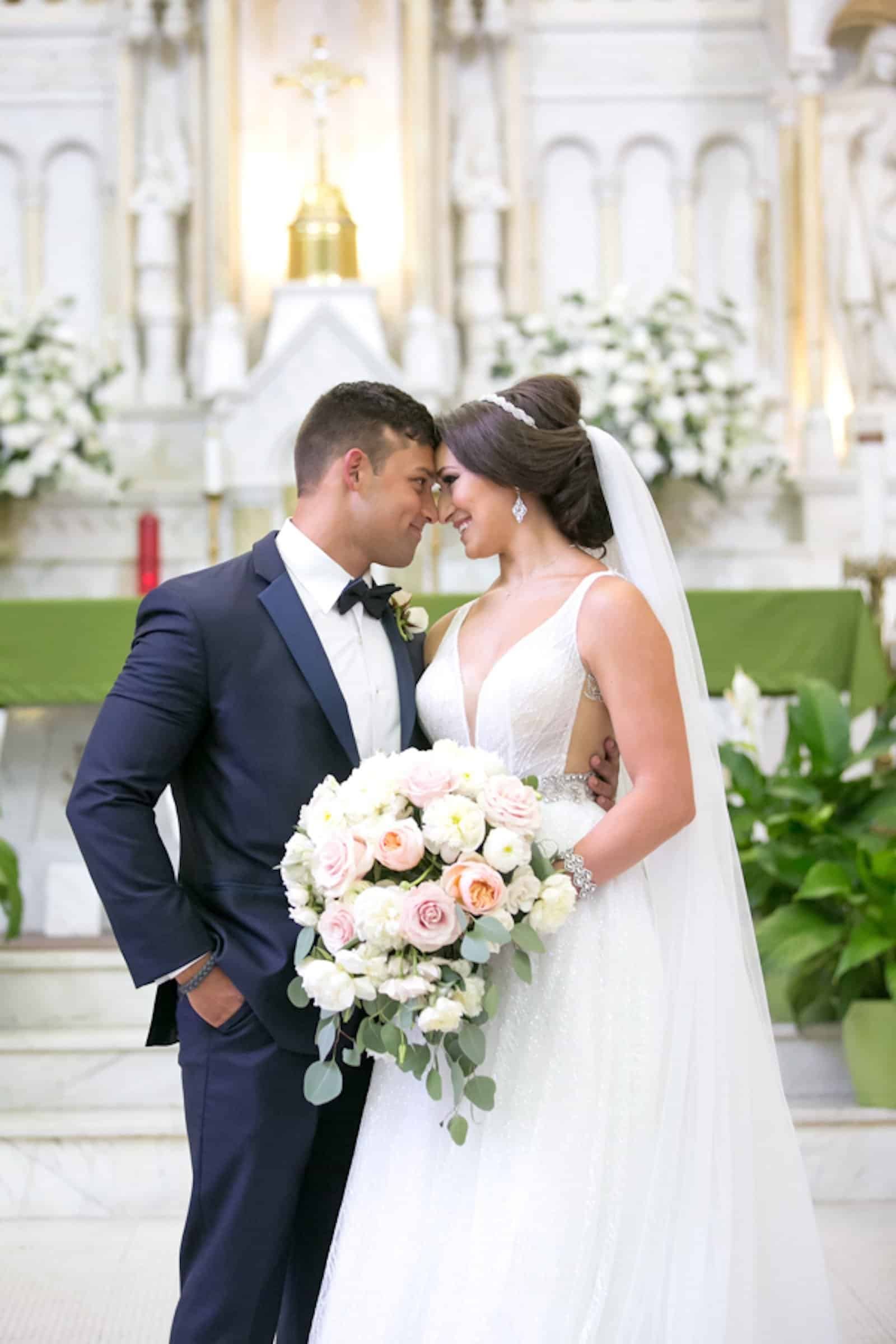 A beautiful four-tier white wedding cake decorated with elegant pink floral arrangements.