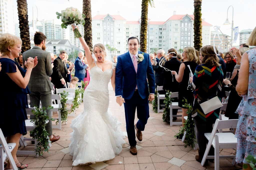 A bride and groom waving from a boat during their wedding night send-off.