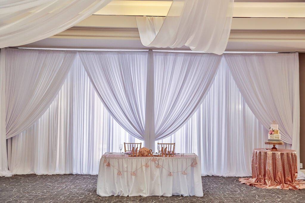 Romantic rose gold and ivory reception table settings with elegant floral centerpieces.