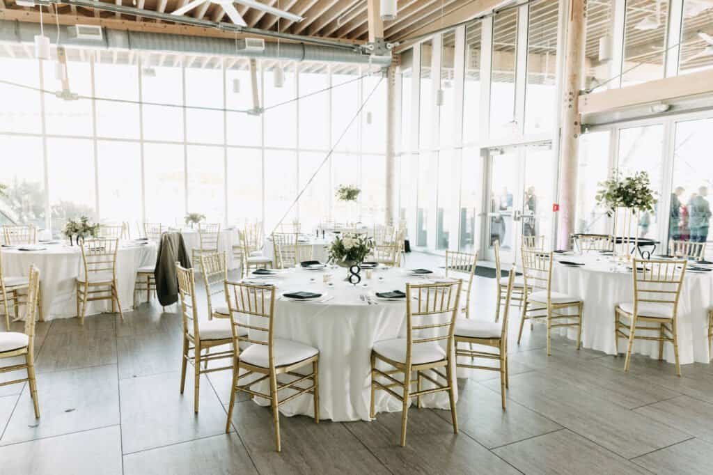 Reception at the Tampa River Center with gold Chiavari chairs at round tables against floor-to-ceiling glass