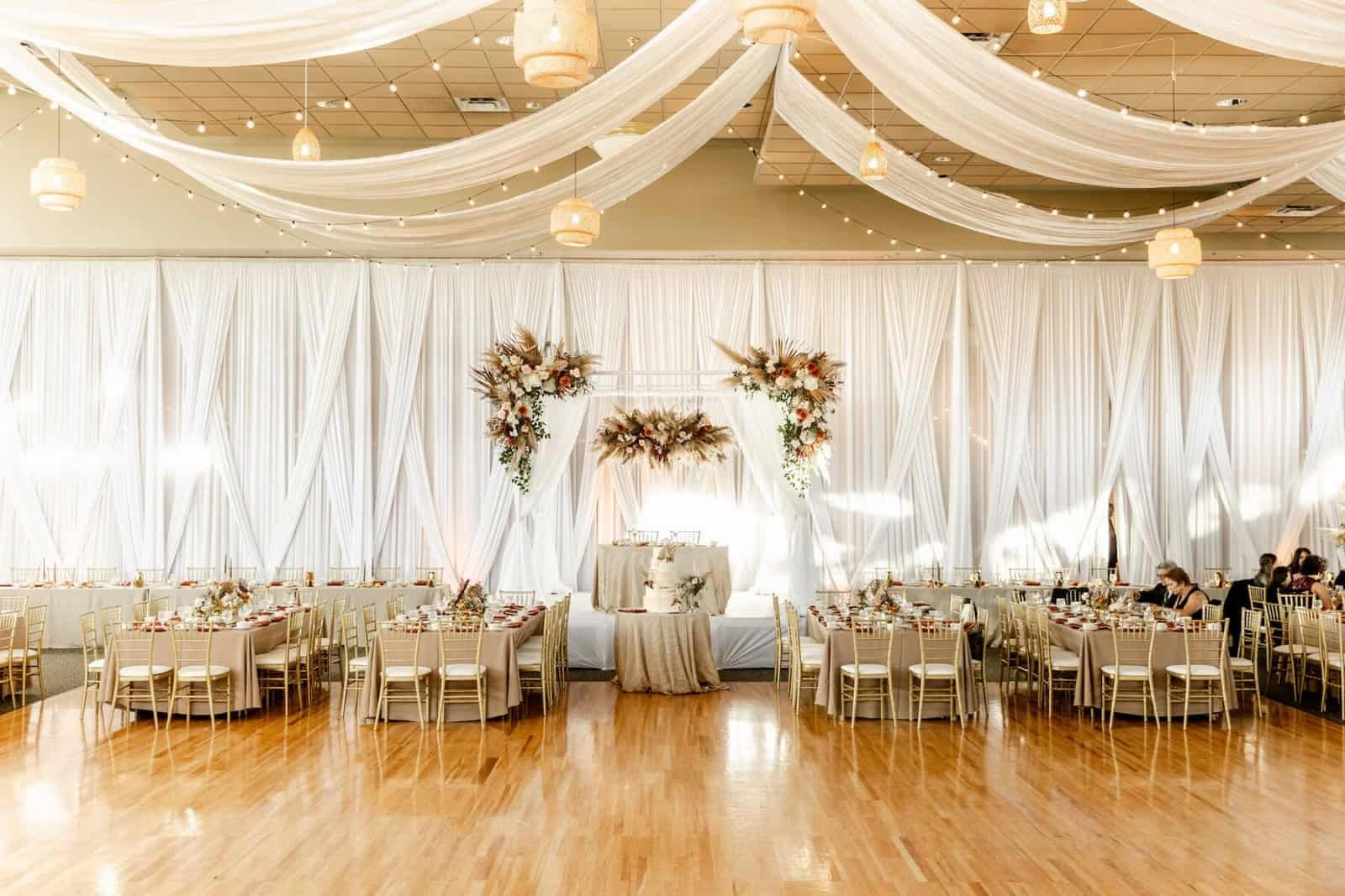 Reception hall in Tarpon Springs with white ceiling drape swagged from the centre, draped walls and gold Chiavari chairs