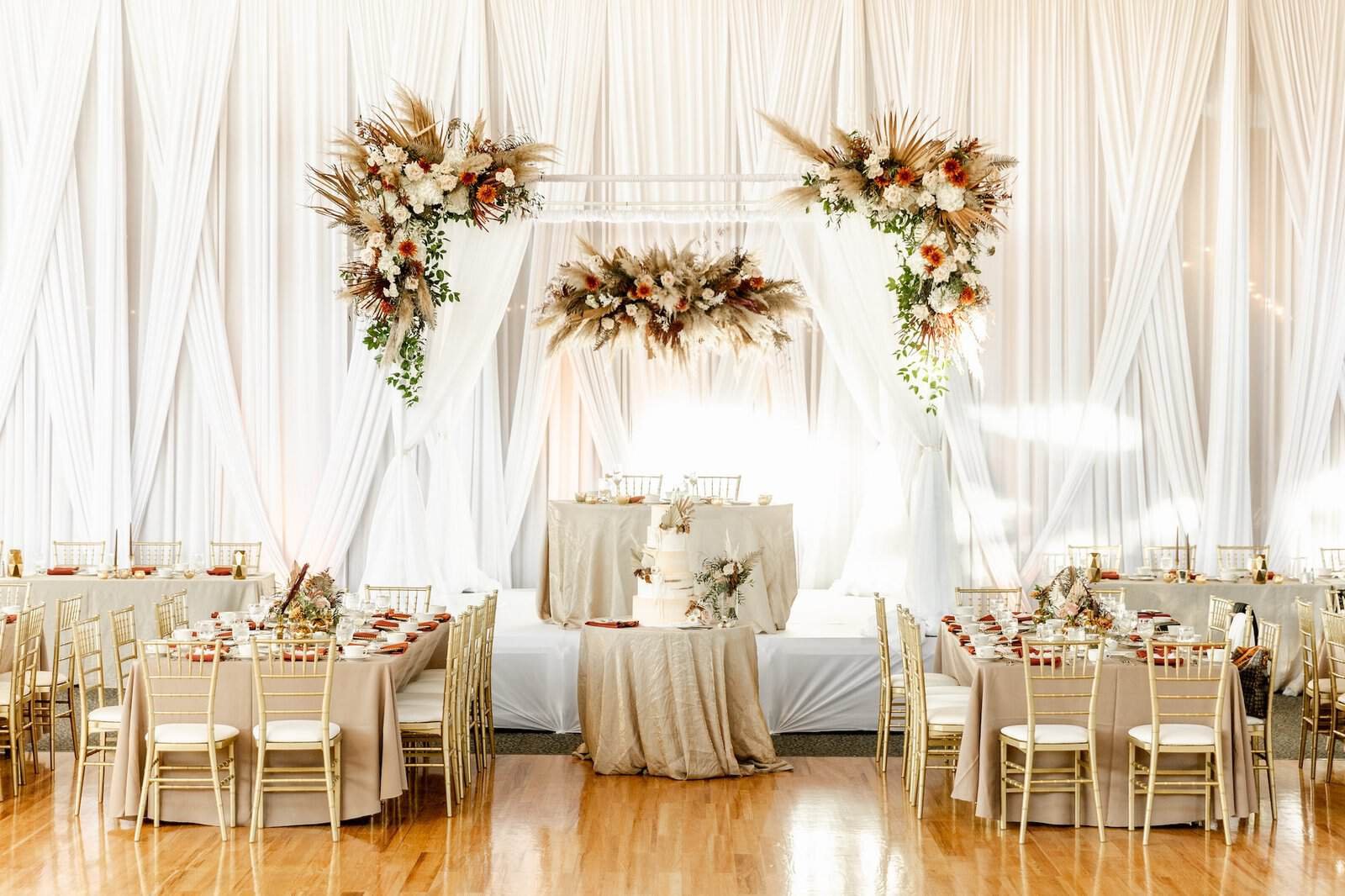 Gold Chiavari chairs at round tables against full-height white draping