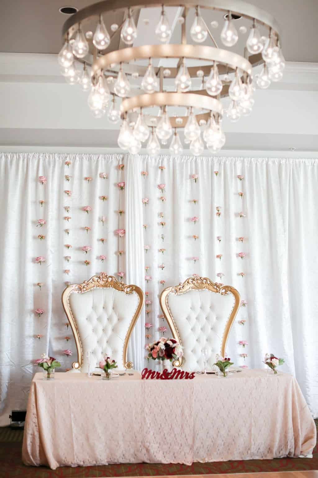 Antique gold sweetheart table chairs with dusty rose linens and elegant white ceiling draping at The Birchwood