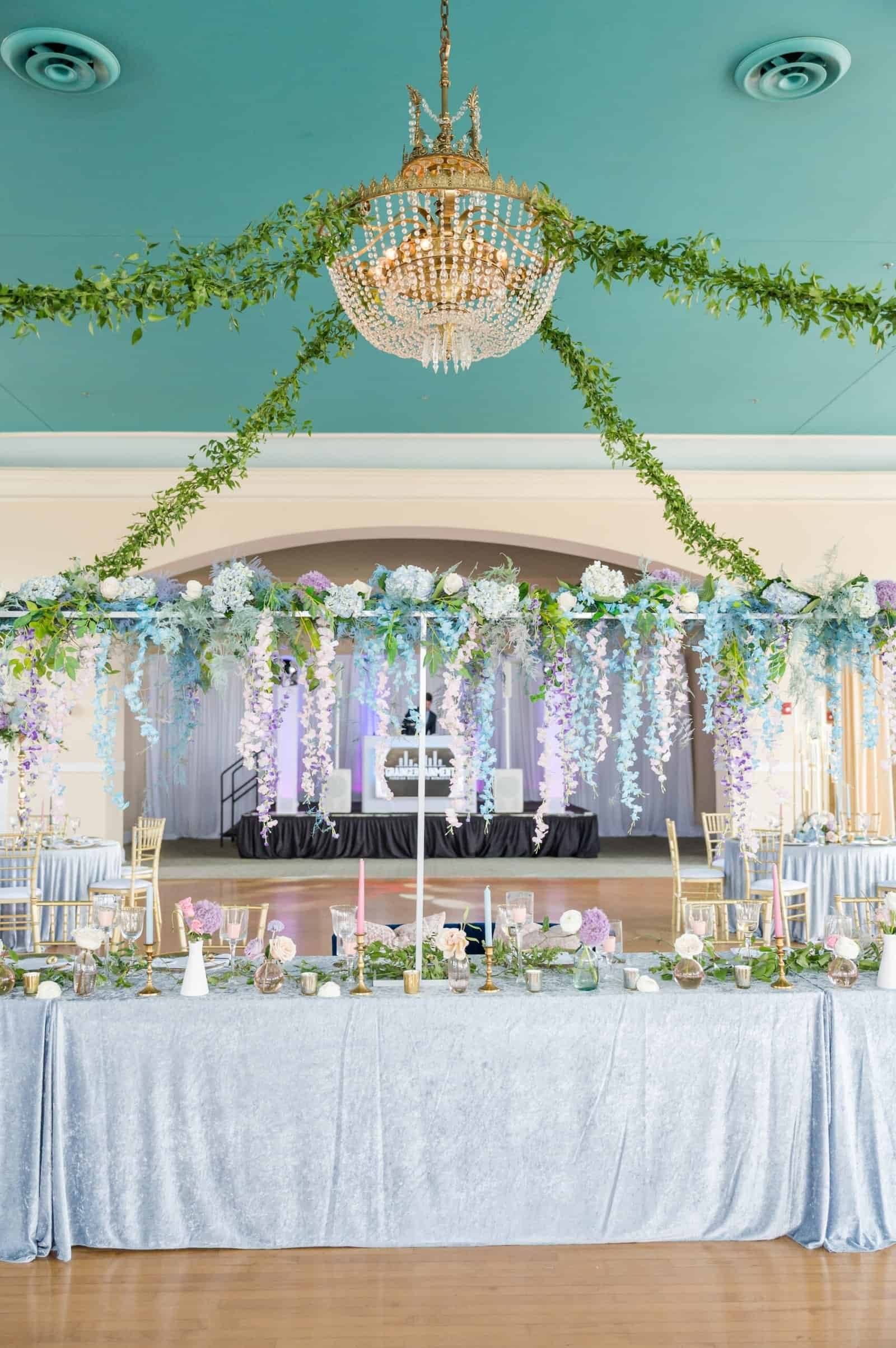 Long banquet tables beneath hanging greenery inside The Cuban Club ballroom