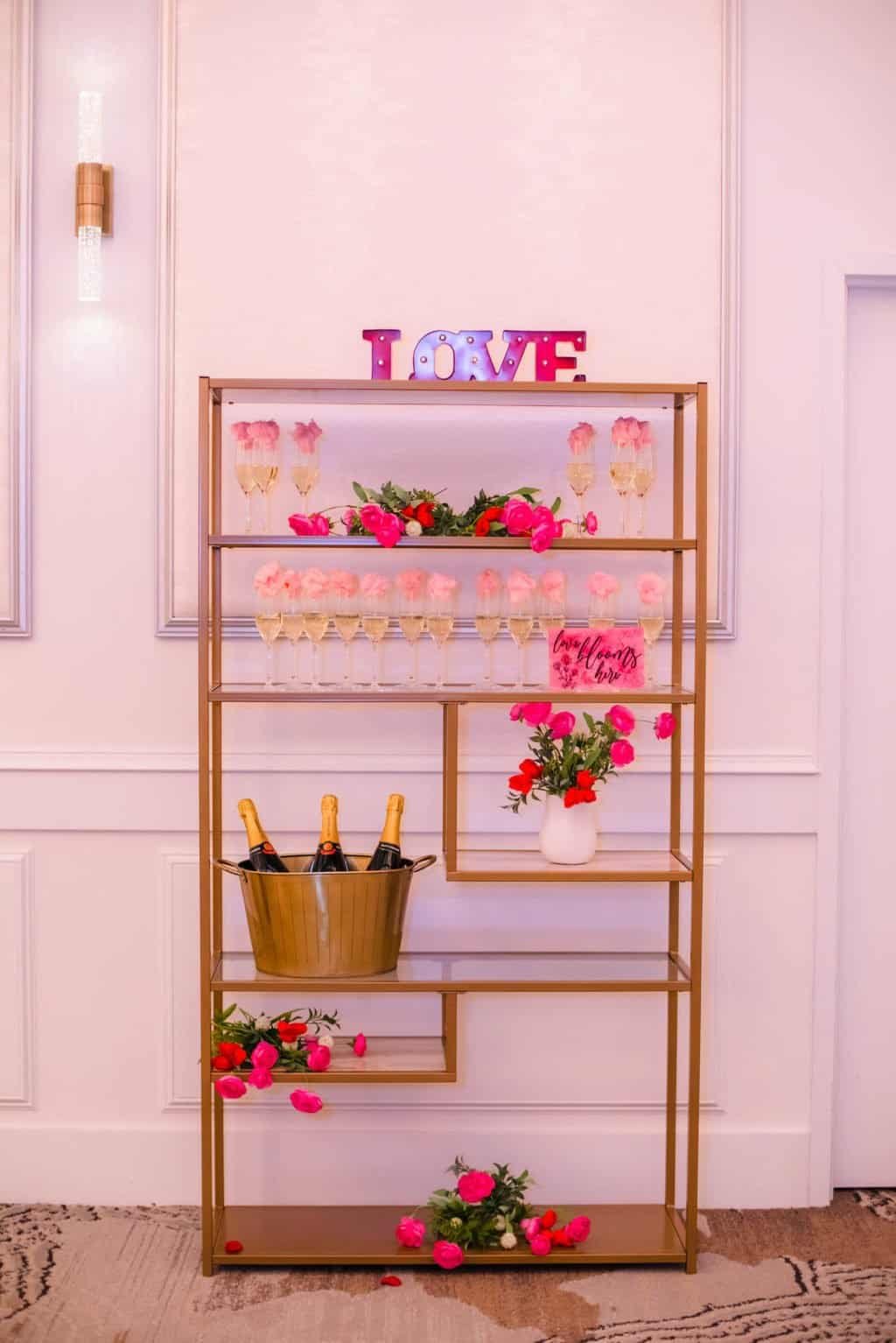 A modern geometric wedding ceremony backdrop featuring an ombre pink and red floral arrangement.
