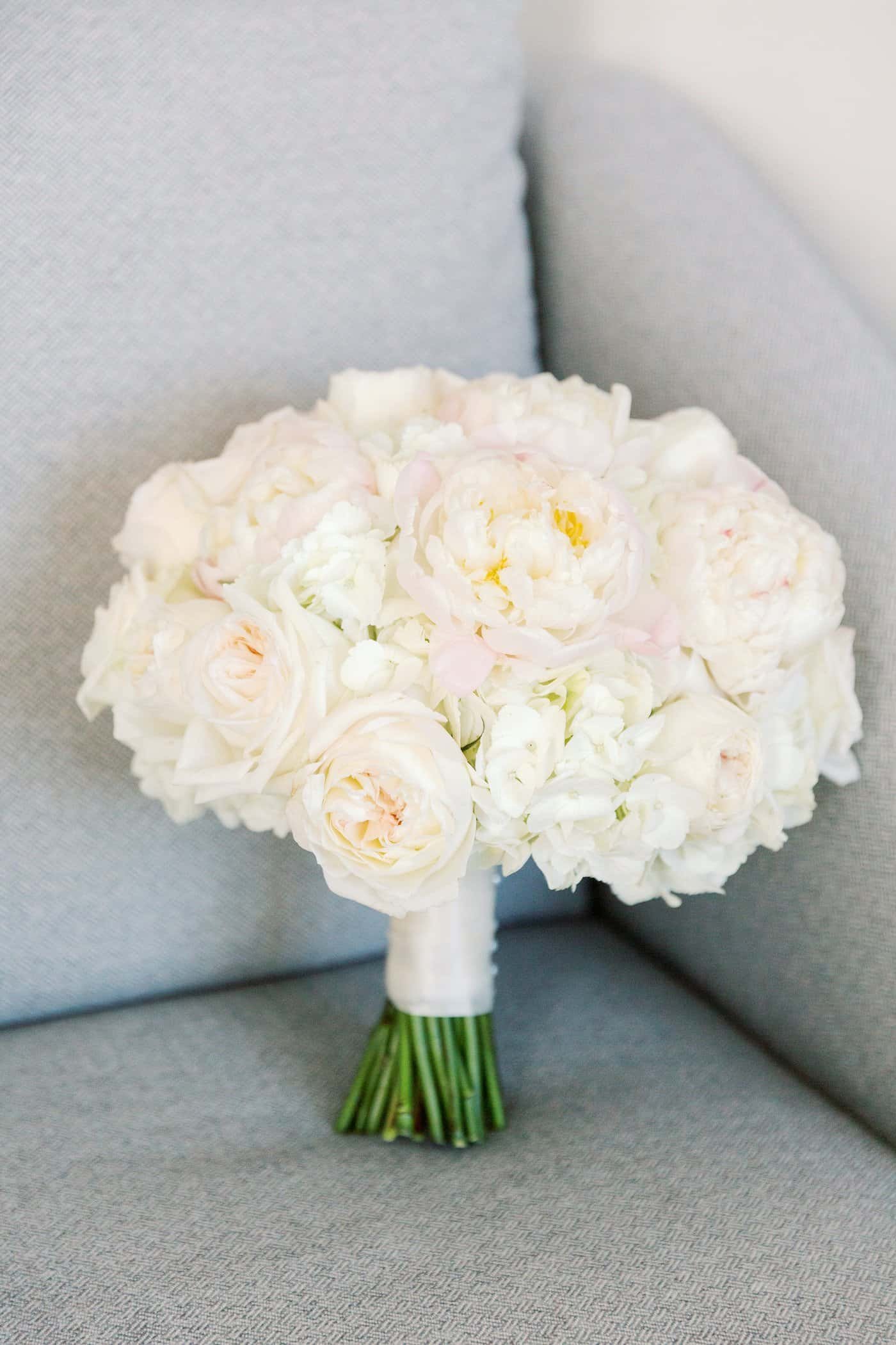 An elegant ballroom reception setup featuring blush florals and gold accents overlooking the bay.