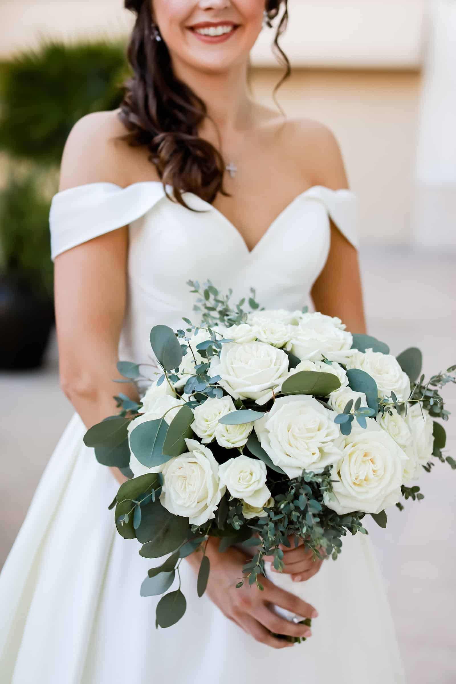 Close up of lush white roses and eucalyptus in a bridal bouquet.