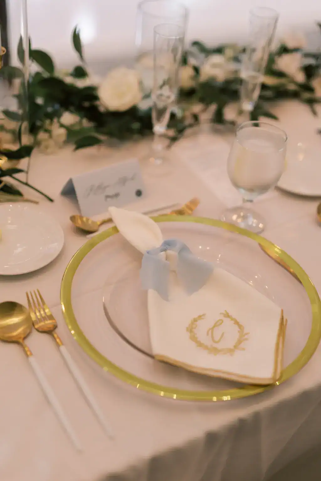 Classic white and gold monogrammed napkins with gold charger and metallic flatware tablescape
