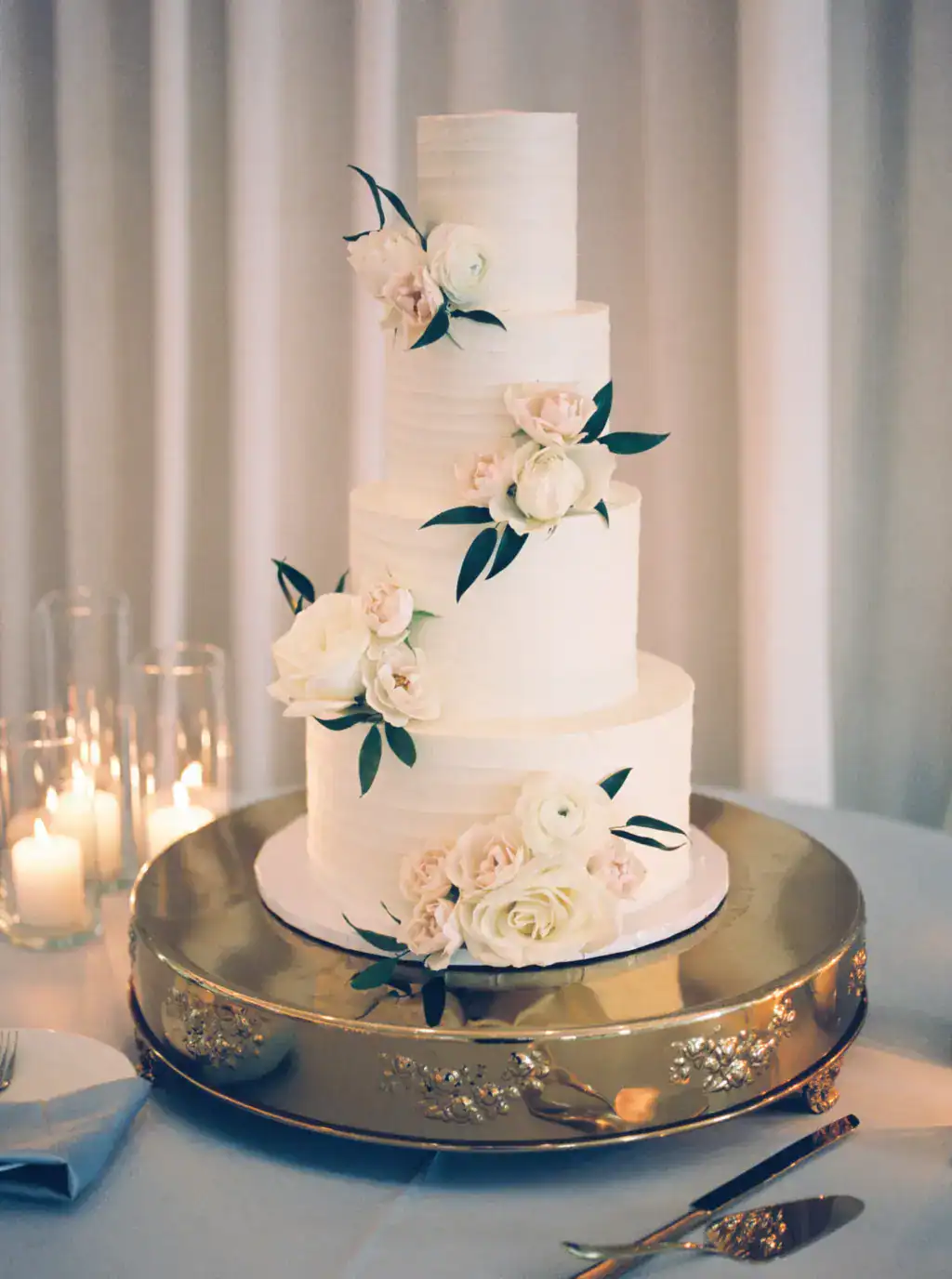 Round four-tier white wedding cake with delicate sugar rose accents by Tampa Bay cake designer