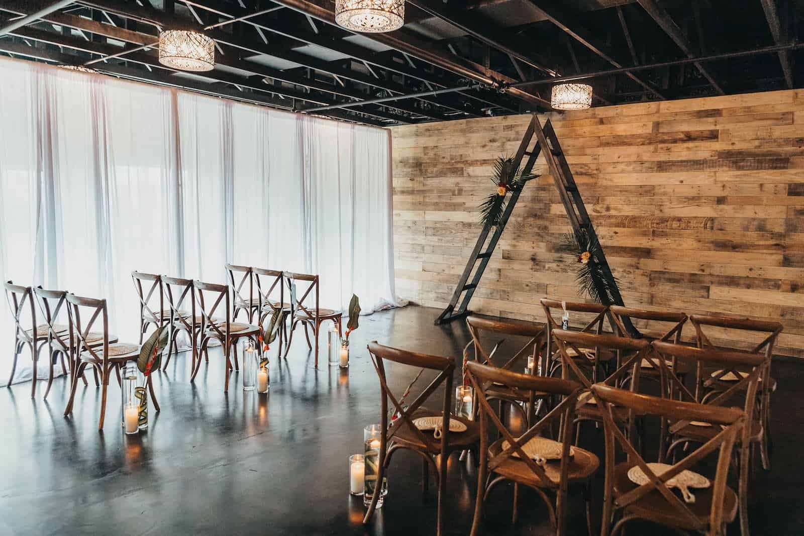 Industrial wedding venue interior featuring tropical greenery and modern black and white accents.