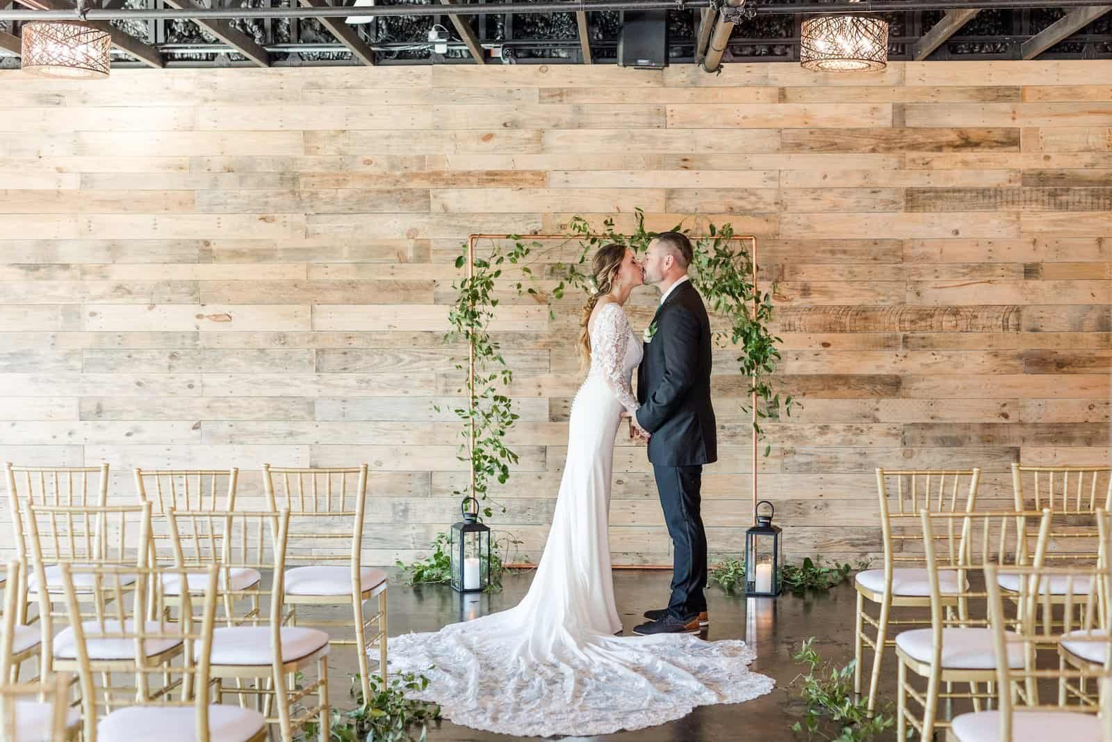 Emerald green linens and clear ghost chairs decorating a moody wedding reception table.