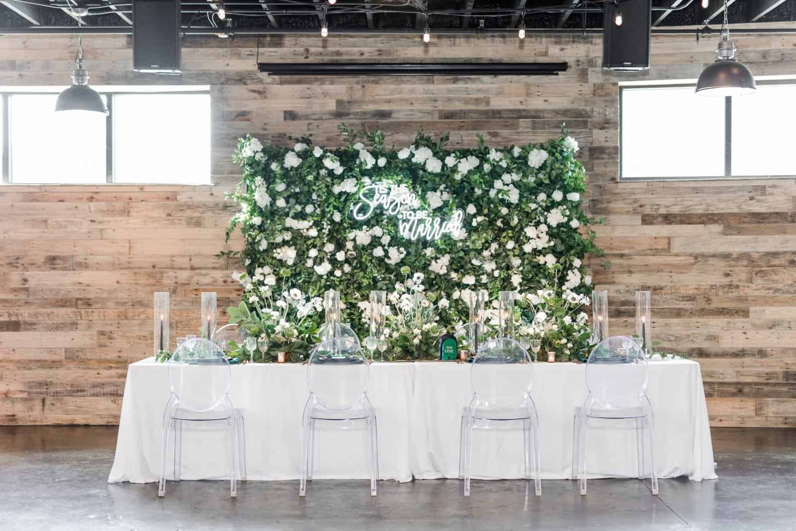 Long head table under white linen with clear acrylic chairs at The West Events Space