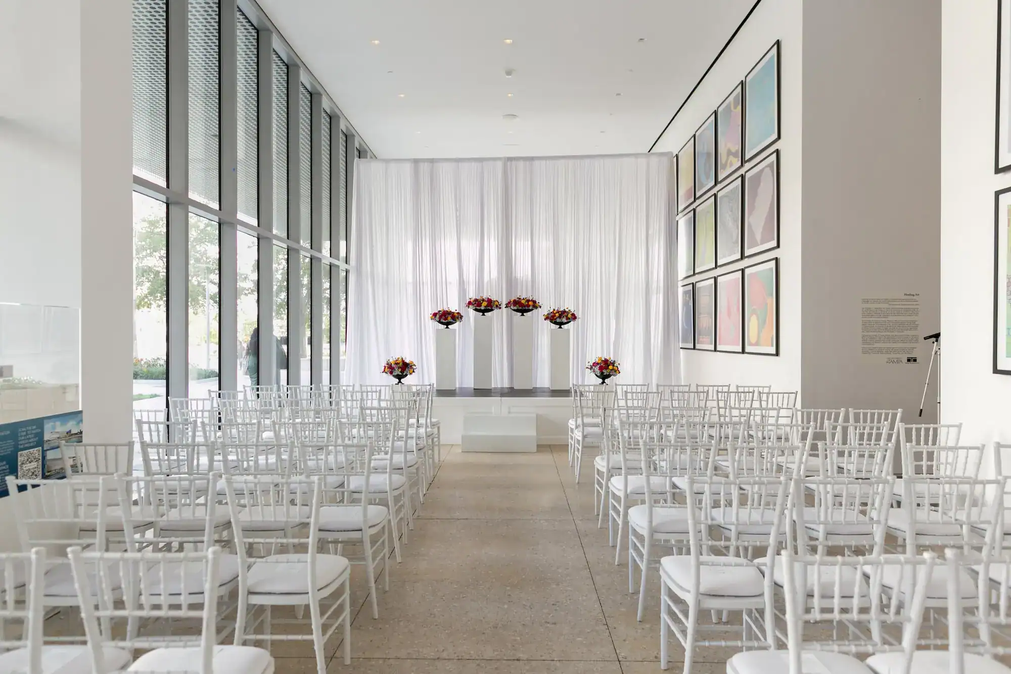Covered terrace ceremony aisle with white chiavari chairs and stage by Gabro Event Services at Tampa Museum of Art