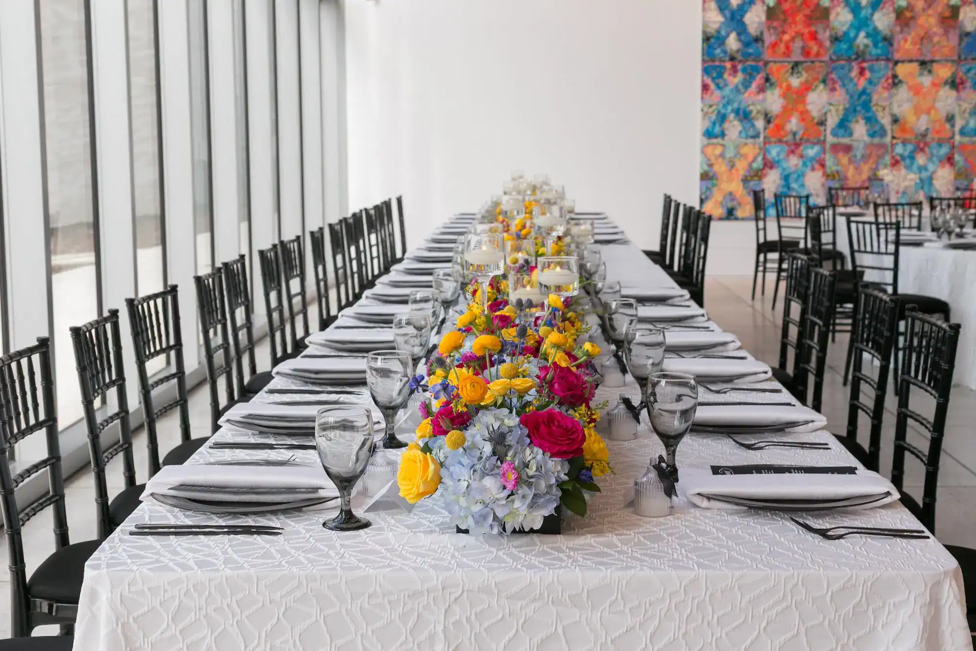 Vibrant feasting tablescape with gold flatware, tinted goblets, and charger plates from Gabro Event Services