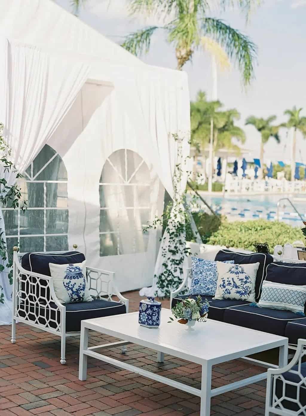 Poolside lounge vignette framed by white drapery panels and palm trees