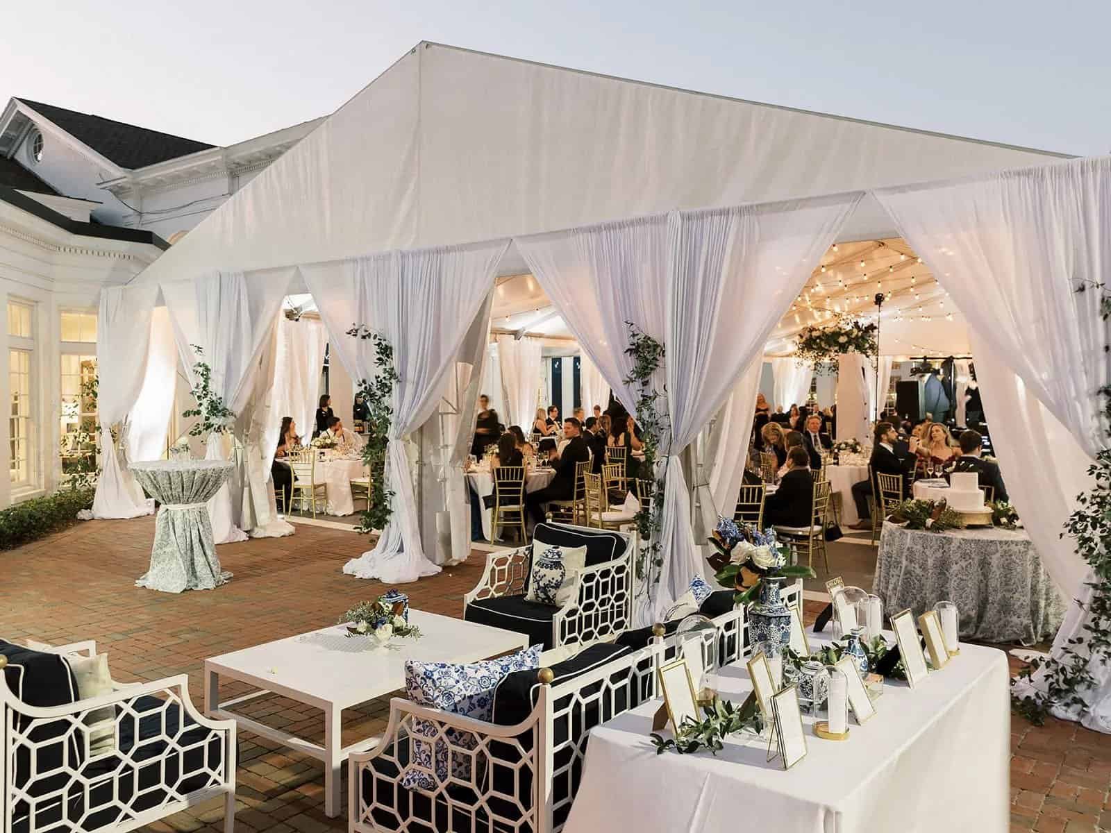White drapery panels tied back at the openings of a tented reception on the pool deck