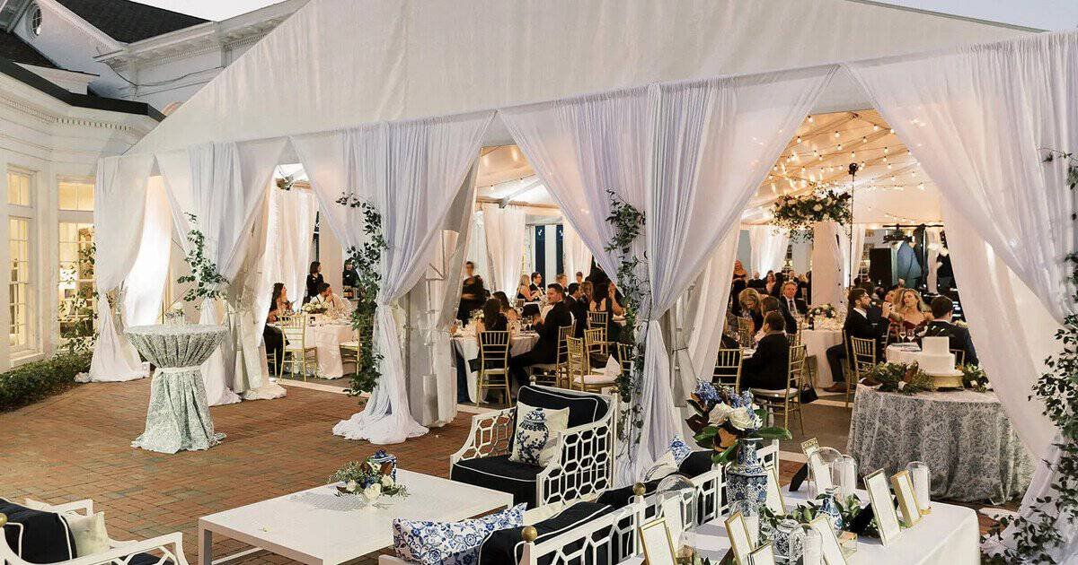 White drapery panels lining a tented waterfront reception with navy and white lounge seating