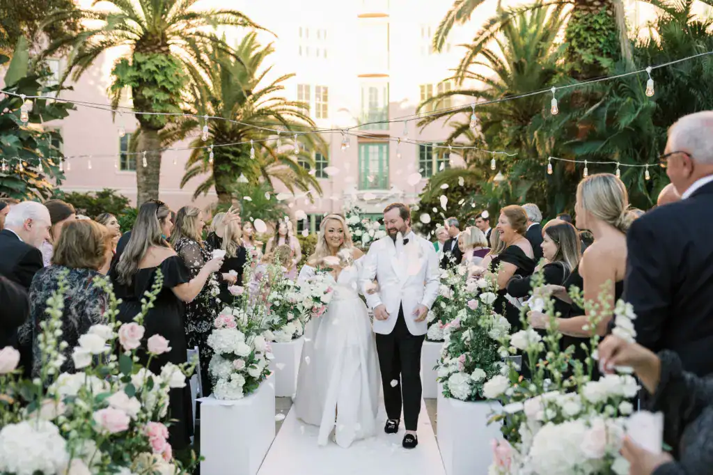 Bride and groom joyful newlywed walk down the petal lined tea garden aisle
