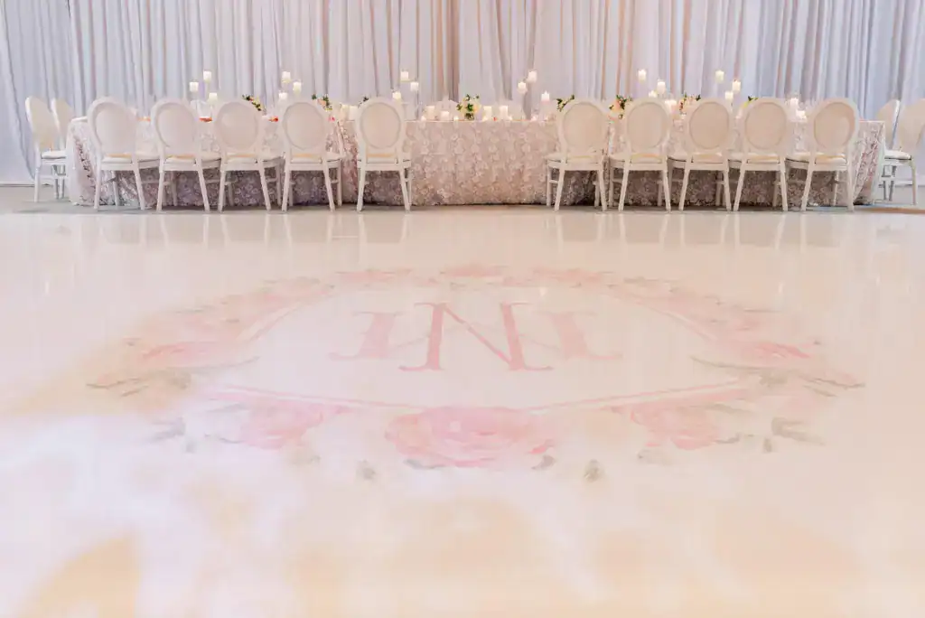 Custom monogram floral dance floor wrap, feasting tables, and ballroom rentals by Gabro Event Services