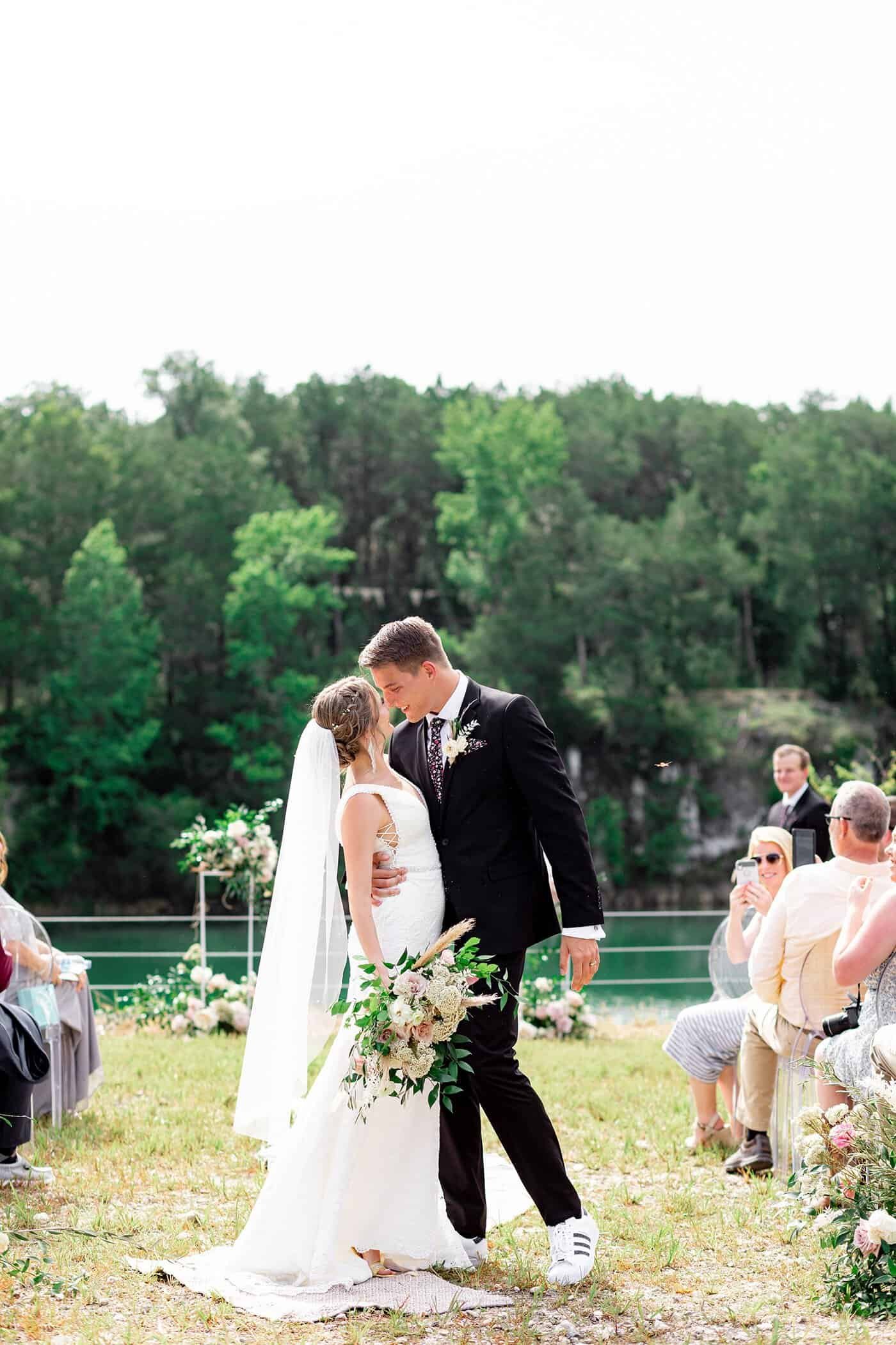 Newlyweds kissing atop the limestone quarry bluff as golden hour light illuminates the Florida sky
