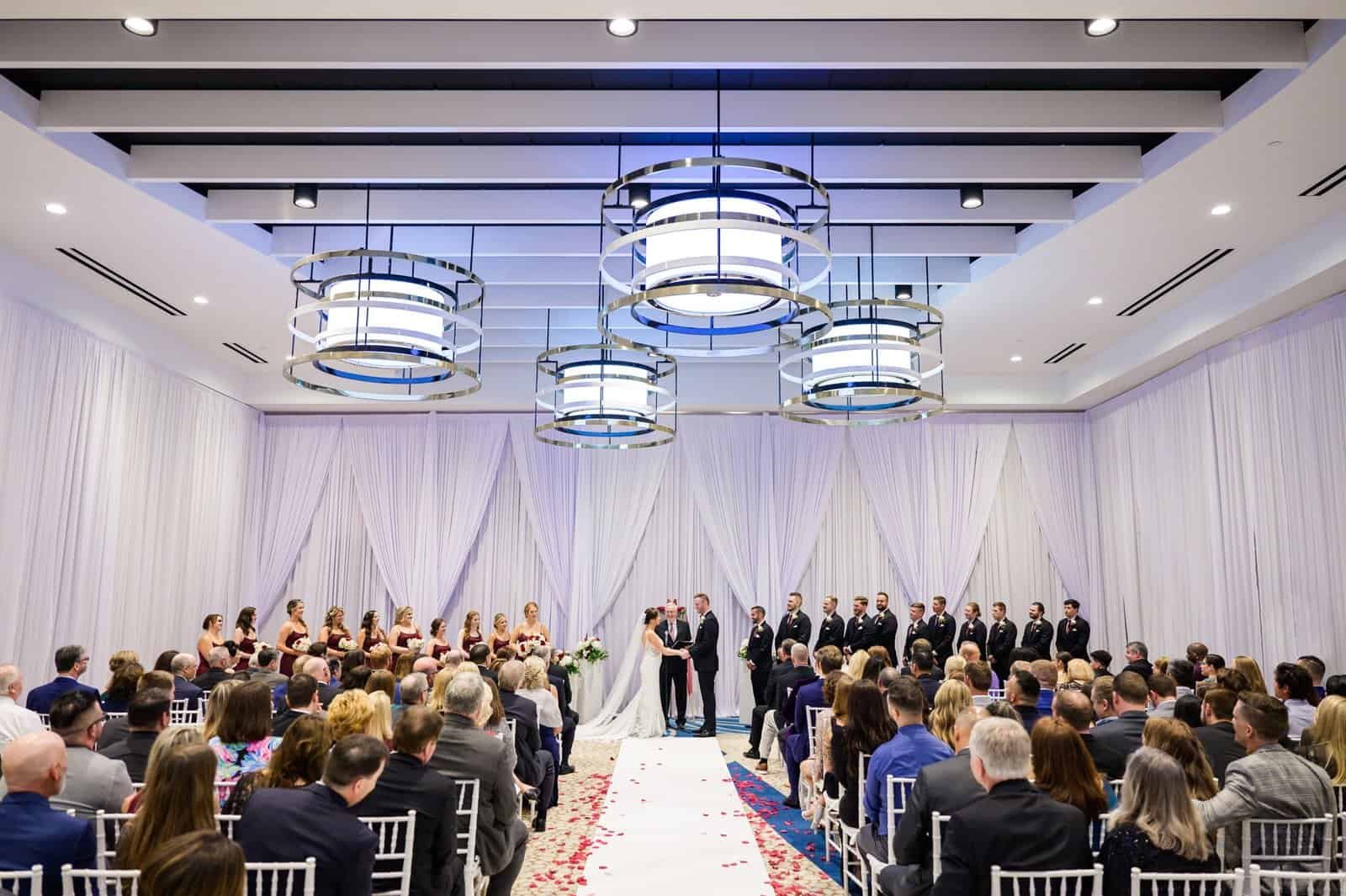 Ceremony room fully draped in white with rows of white Chiavari chairs at the Wyndham Grand Clearwater Beach