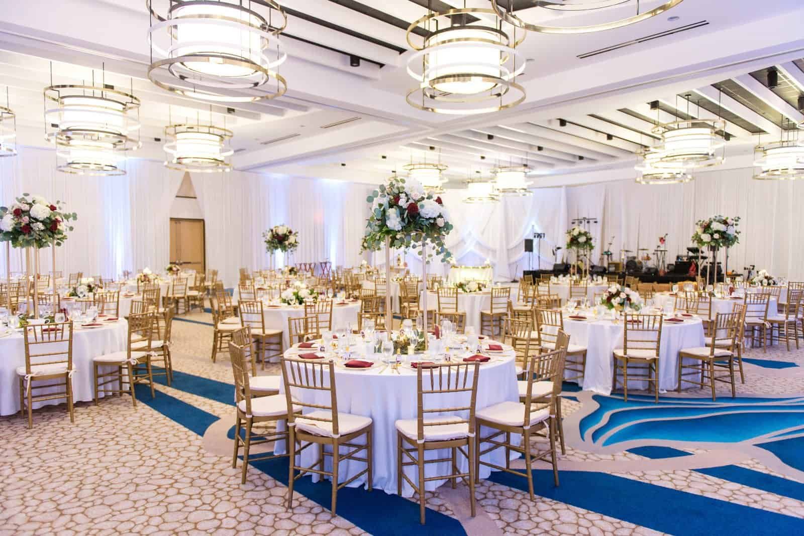 Reception at the Wyndham Grand Clearwater Beach with gold Chiavari chairs at round tables against draped walls